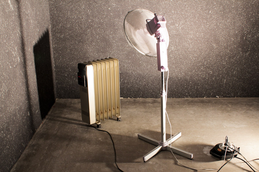Eine mobiles Heizgerät und ein Ventilator vor einer mit Baumwollputz verkleideten Wand.