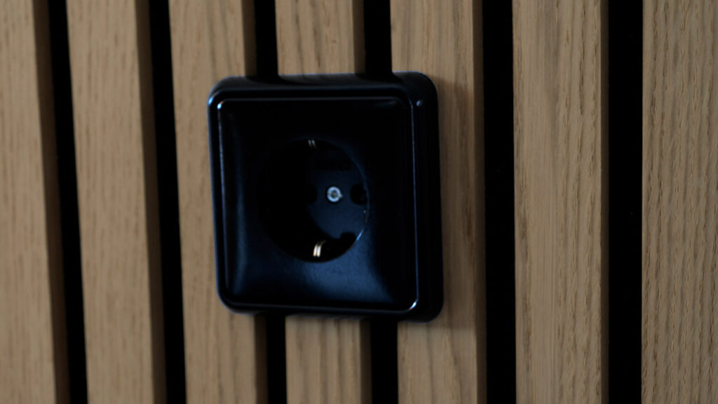 Die fertige Steckdose mit schwarzer Abdeckung vor einem Akustikpaneel
